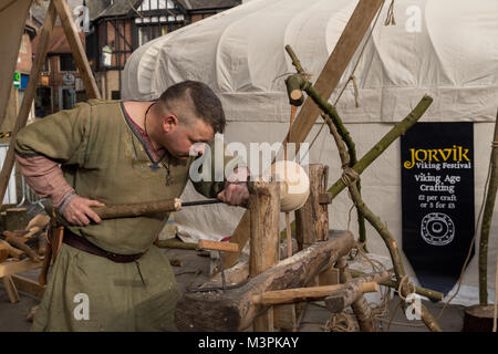 York, UK, 12. Februar 2018, Person, gekleidet wie ein Wikinger auf der jährlichen Jorvik Viking Festival in der Innenstadt von York statt. Dieser Mann ist ein erfahrener Drechsler & ist die Konzentration auf Handarbeit eine hölzerne Schüssel, mit einem einfachen Drehbank & handgefertigte Werkzeuge. Er beteiligt sich an der realistischen Re-enactment von Leben bei einem Viking Markt. North Yorkshire, England, UK. Credit: Ian Lamond/Alamy leben Nachrichten Stockfoto