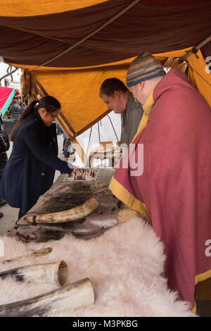 York, UK, 12. Februar 2018, verkleidet als Wikinger am jährlichen Jorvik Viking Festival. Ein weibliches Mitglied der Öffentlichkeit ist ein Spiel der hnefatafl mit einem der Männer. Artikel am Stall sind von der tierischen Haut und Knochen und Geweih. Beide sind die Teilnahme an einem realistischen Re-enactment von Leben bei einem Viking Markt. Stadtzentrum von York, North Yorkshire, England, UK. Credit: Ian Lamond/Alamy leben Nachrichten Stockfoto