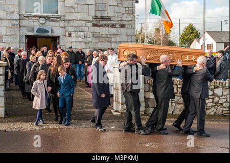 Öfen, Irland. 12 Feb, 2018. Die Beerdigung von spielergebnissen Liam Miller nahm heute am St. Johannes der Täufer Kirche, Öfen, County Cork, Irland, statt. Eine große Anzahl von Trauernden nahmen an der Beerdigung, darunter viele Fußballer aus alten Miller's Clubs, darunter die Stadt Cork, Keltische und Manchester United. Der Sarg von Liam Miller ist zu seiner letzten Ruhestätte auf dem Friedhof in St. Johannes der Täufer Kirche durchgeführt. Miller's Frau Clare, Söhne Korey und Leo und Tochter Belle kann direkt hinter dem Sarg gesehen werden. Credit: Andy Gibson/Alamy Leben Nachrichten. Stockfoto