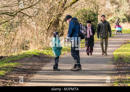 East Lothian, Schottland, Großbritannien, 12th. Februar 2017. Ein Großvater und sein sechsjähriger Enkel genießen einen Spaziergang entlang eines Flusswegs auf dem Fluss Esk, wobei ein älteres Paar und eine Frau einen Doppelbuggy ebenfalls auf dem Weg schieben. Der Junge hat Zerebralparese und trägt eine Beinstrebe aus Kohlefaser für eine rechte Hemiplegie Stockfoto