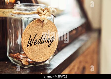 Vintage Retro Glas Glas mit hanfseil Krawatte Hochzeit Tag und paar Münzen Innen auf Holz Zähler Konzept, um das Geld für die Hochzeit Stockfoto