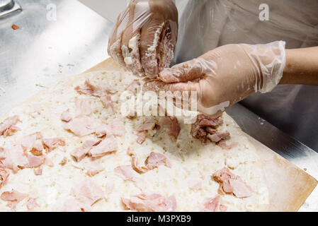 Weibliche Hände in Latex Handschuhe, Verzieren Pizza. Stockfoto