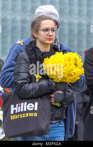 Warschau, Polen - 19 April, 2017: junge Frau hält einen Strauß gelber Narzissen während einer Zeremonie an der Warschauer Ghetto Helden Denkmal. Stockfoto