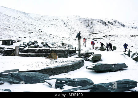 Wanderer begeben sich auf eine Wanderung im Schnee von Honister Schiefergrube im Lake District in Cumbria, wie Pendler auf Eisglatten Montag morgen konfrontiert, mit schweren Schnee in Teilen von Schottland erwartet trotz Warnungen von Fahrzeugen gestrandeten immer auf Straßen. Stockfoto