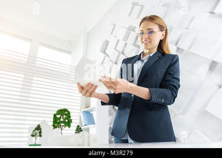 Froh, Ingenieur am Tisch mit einem kleinen Haus Stockfoto