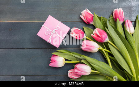 Tag der Frauen. Rosa Tulpen Bouquet und einem rosa Geschenk auf blauem Hintergrund Holz, Kopieren, Ansicht von oben Stockfoto