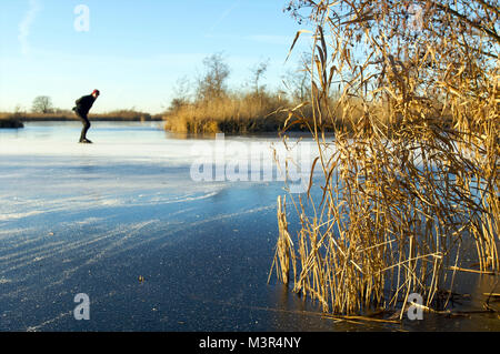 Man Schlittschuhlaufen auf dem Eis in der Natur während eines kalten Winters in den Niederlanden Stockfoto