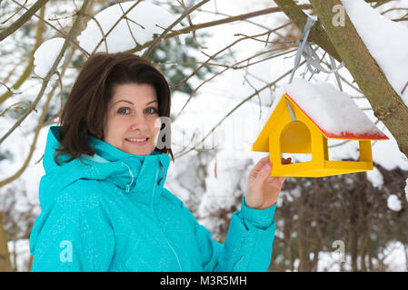 Frau steht in der Nähe von Yellow Bird Feeder Stockfoto