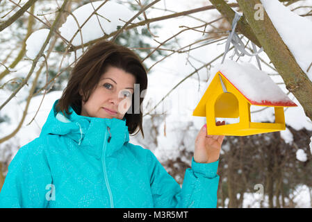 Frau steht in der Nähe von Yellow Bird Feeder Stockfoto