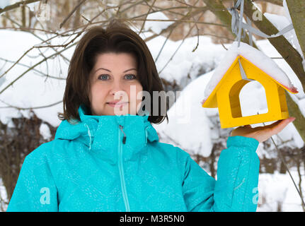 Frau steht in der Nähe von Yellow Bird Feeder Stockfoto