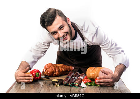 Koch auf weißem Hintergrund, Kamera und lächelnd, Salami umarmen Stockfoto