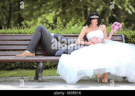 Bräutigam und Braut entspannt auf einer Parkbank Stockfoto