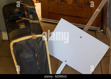 Warnen, Retro alte Pappe Koffer und eine leere weiße Sicherheitsplakette außerhalb eine offene Tür Bild im Querformat. Stockfoto
