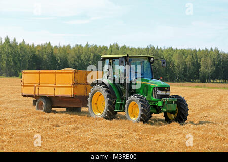 RAASEPORI, Finnland - 17. AUGUST 2014: Nicht identifizierte Bauer fahren eines John Deere 5820 Traktoren und Anhänger voller Körner. John Deere 5820 wa Stockfoto