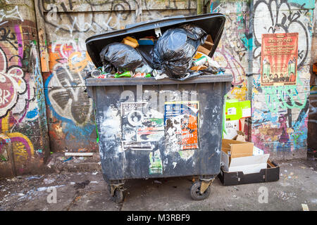 Handel watse Fächer voll Müll Müll auf der Straße, mit Grafitti uk Stockfoto