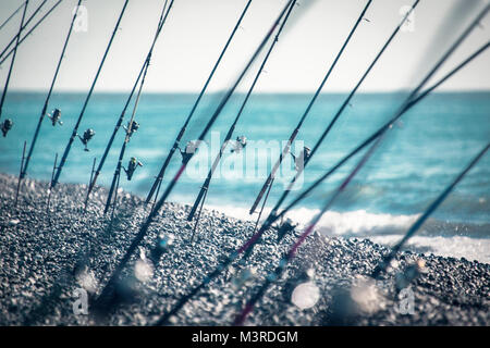 Angeln Pole auf der Halterung montiert und Eingestellt am Ufer eines Meeres getönt Stockfoto