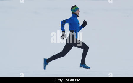 Jungen männlichen Athleten laufen schnell im Winter durch die verschneite Eis Feld Stockfoto