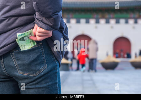 Mann zieht der koreanischen Geld von seiner Jeans Tasche an Gyeongbokgung Palast, Seoul Korea Stockfoto