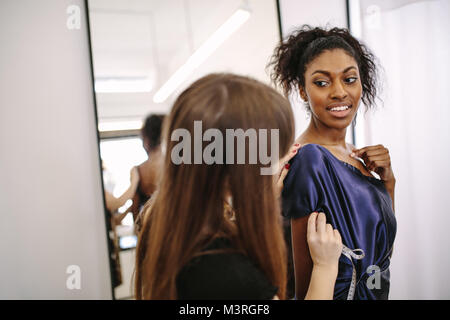 Fashion Designer versuchen, neue Designer Kleidung auf einem Modell. Frau Unternehmer in ihr Tuch Shop Design neuer Kleidung. Stockfoto