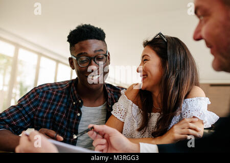 Happy interracial Paare an ihrem neuen Haus Mietvertrag schauen und lächelnd mit Immobilien Makler. Junges Paar Vermietung ein neues Haus. Stockfoto
