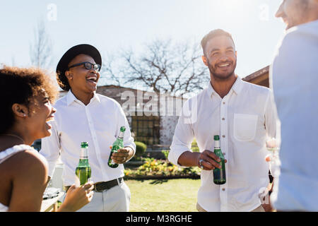 Gruppe von jungen Freunden trinken und Geselligkeit. Junge Männer und Frau, die Party im Freien im Sommer. Stockfoto