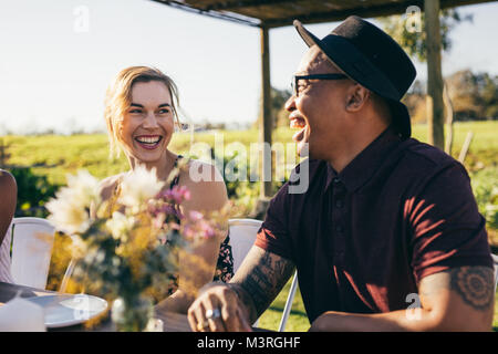 Afrikanischer Mann lacht während einer Partei. Fröhlicher junger Kerl mit Freunden im Garten Restaurant. Stockfoto