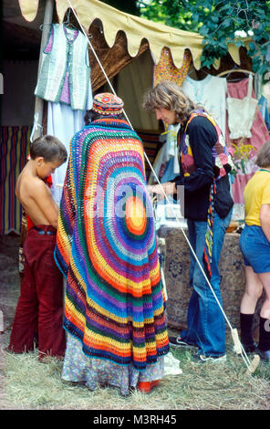 Frau in einem farbenfrohen Regenbogen-Häkeltuch, die Kunsthandwerk in einem Stallladen beim Barsham Fair Medieval Music Festival 1974 in Beccles Suffolk England 70s 1970s KATHY DEWITT ansieht Stockfoto