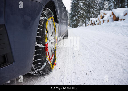 Steiermark, Österreich - Februar, 2017: Schneeketten auf vorderen Reifen im Winter mit Schnee und Eis montiert. Stockfoto