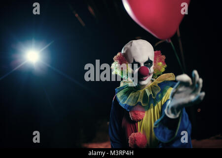 Bild der Clown mit roten Luftballon auf dem Hintergrund der brennenden Laterne Stockfoto