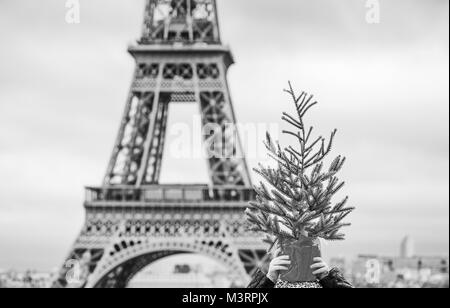 Die Party Saison in Paris. Closeup auf glückliches trendige Kind vor Eiffelturm in Paris, Frankreich-Holding-Weihnachtsbaum auf Kopf Stockfoto