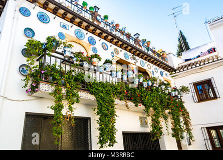 Granada, Spanien: Fassade eines traditionellen Hauses mit dekorativen keramischen Platten an der Wand und auf den Balkonen voller Töpfe mit bunten Blumen in der historischen Stockfoto