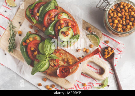 Vegetarisches Sandwich mit Tomate, Gurke, frittierte Kichererbsen und Basilikum öffnen. Gesunde vegane Ernährung Konzept. Stockfoto