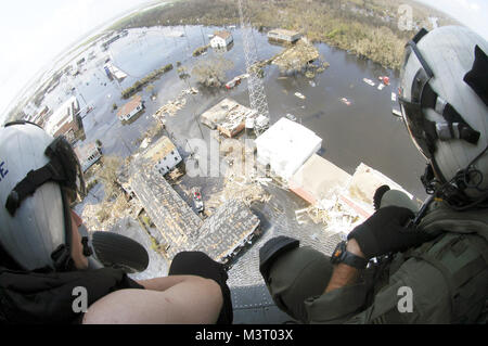 Zwei der US Navy (USN) Suche und Rettung (SAR) Schwimmer, Hubschrauber Meer Combat Squadron 28 (HSC-28), sehen Sie sich eine Rettung entfalten, während auf dem Deck der USN Sikorsky MH-60S Seahawk Hubschrauber sitzt, um zu sehen, wenn ihre Hilfe benötigt wird. Diese Schwimmer sind Teil der Joint Task Force (JTF) Katrina, die humanitäre und Soforthilfe an der Golfküste Opfer von Hurrikan Katrina. 330-CFD-DN-SD -06-03455 durch Foto Kurator Stockfoto
