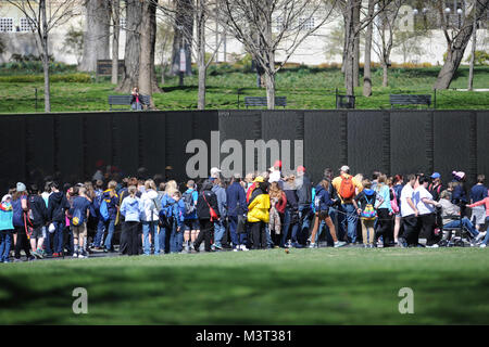 Auf nationaler Vietnam Veterans Day, Familienmitglieder, Touristen und Besucher zu Washington D.C. zahlen ihren Respekt für die gefallenen Helden des Vietnam Krieges am Denkmal der Vietnam Veteran auf der National Mall entfernt. Die Mauer der Erinnerung besteht aus zwei 246 Fuß 9 Zoll (75.21 m) langen gabbro Wänden aus, mit den Namen der Soldaten in horizontalen Zeilen mit regelmäßigen Schrift und Zeilenabstand geehrt wird geätzt. Die Wände sind in den Boden versenkt, mit der Erde hinter Ihnen. Auf der höchsten Spitze (apex, wo Sie sich treffen), sind sie 10,1 Fuß (3,1 m) hoch, und sie zu einer Höhe von 8 inkl Konus Stockfoto