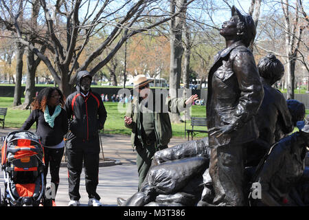 Besucher und Touristen in Scharen zur National Mall, Memorial Statue die Vietnam Women's auf nationalen Vietnam Veterans Day zu besuchen. Die Statue auf der National Mall in Washington D.C. in der Nähe von Mauer der Erinnerung der Vietnam Veteran befindet. Die Vietnam Women's Memorial ist ein Denkmal für die Frauen in den Vereinigten Staaten, die im Vietnam Krieg diente, von denen die meisten waren Krankenschwestern gewidmet. Es dient als Erinnerung, die Bedeutung der Frauen in den Konflikt. Es zeigt drei Uniformierten Frauen mit einem verletzten Soldaten. Es ist Teil des Vietnam Veterans Memorial, und ist auf der National Mall in Washington D.C., Sho entfernt Stockfoto