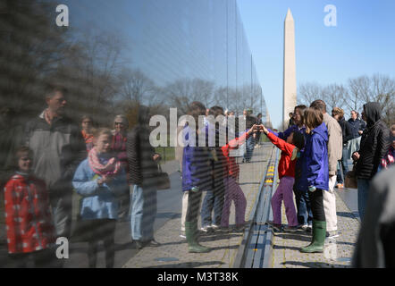 Auf nationaler Vietnam Veterans Day, Familienmitglieder, Touristen und Besucher zu Washington D.C. zahlen ihren Respekt für die gefallenen Helden des Vietnam Krieges am Denkmal der Vietnam Veteran auf der National Mall entfernt. Die Mauer der Erinnerung besteht aus zwei 246 Fuß 9 Zoll (75.21 m) langen gabbro Wänden aus, mit den Namen der Soldaten in horizontalen Zeilen mit regelmäßigen Schrift und Zeilenabstand geehrt wird geätzt. Die Wände sind in den Boden versenkt, mit der Erde hinter Ihnen. Auf der höchsten Spitze (apex, wo Sie sich treffen), sind sie 10,1 Fuß (3,1 m) hoch, und sie zu einer Höhe von 8 inkl Konus Stockfoto