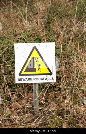 Schild „Vorsicht vor den Rockfalls“ auf dem South Beach Studland unter den zerklüfteten Klippen an der Dorset-Küste. Gesundheits- und Sicherheitshinweis für die Öffentlichkeit. Stockfoto