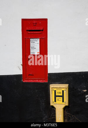 Red Victorian postbox und gelben Hydranten Marker schwarz und weiß gestrichenen Wand, Bath, Devon, Großbritannien. Stockfoto