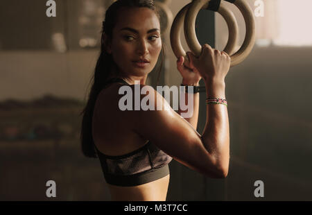 Bestimmt Frau Trainieren mit Gymnastik Ringe in der Turnhalle. Weibliche Athleten stehen im Fitnessstudio Holding dip-Ringe. Stockfoto