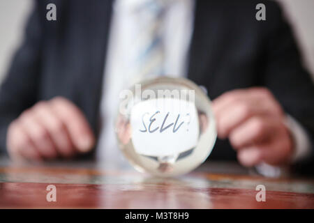 Nahaufnahme der Mann hält Papier mit Word vor glas kugel Verkaufen Stockfoto