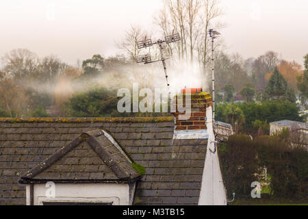 Weiß smore, die aus dem Schornstein eines alten Landhaus mit TV Antennen Stockfoto