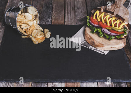 Classic Hot Dog mit Pommes frites auf dunklem Hintergrund. Tischplatte, Vorderansicht. Stockfoto