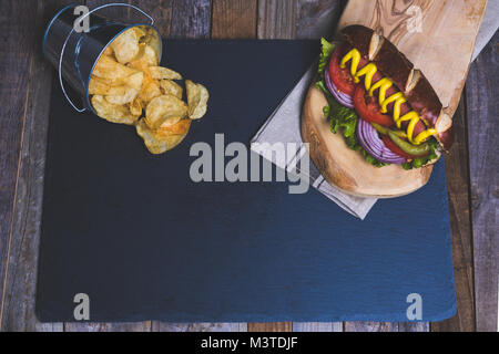 Classic Hot Dog mit Pommes frites auf dunklem Hintergrund. Tischplatte, Ansicht von oben. Stockfoto