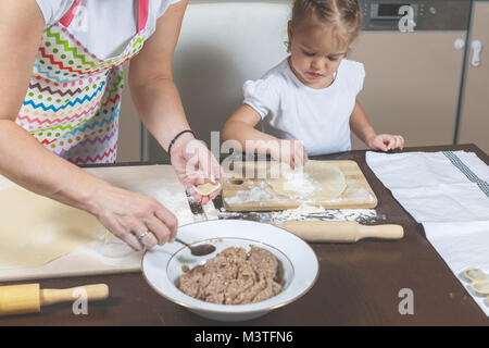 Kleine Mädchen und Mama Knödel machen in der Küche zu Hause. Stockfoto