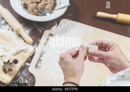 Weibliche Hände Schimmel hausgemachte Knödel auf dem Hintergrund einer hölzernen Tisch Stockfoto