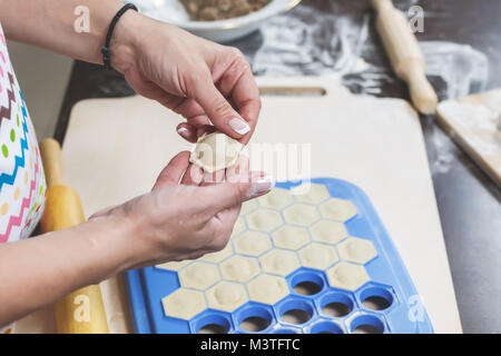 Der Prozess, in dem köstliche hausgemachte Knödel. Weibliche Hände halten frisch Knödel auf dem Hintergrund der Küche Arbeitsbereich Stockfoto