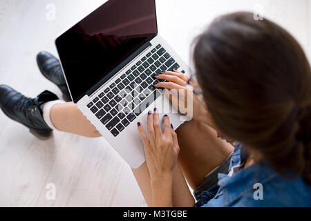 Close-up Portrait von womans Hände an Ihrem Laptop Tastatur, Touchpad Berühren mit den Fingern beim Sitzen auf weißen Boden, mit denen die Computer auf Stockfoto