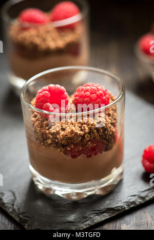 Dessert Schokolade in Gläsern mit Himbeeren. Mousse au Chocolat oder Pudding in Teil Gläser mit frischen Beeren, hautnah. Stockfoto