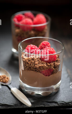 Dessert Schokolade in Gläsern mit Himbeeren. Mousse au Chocolat oder Pudding in Teil Gläser mit frischen Beeren, hautnah. Stockfoto