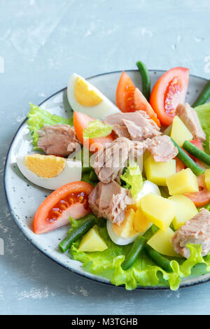 Nicoise Salat mit Thunfisch, Eier, Kartoffeln, grüne Bohnen und Tomaten. Traditionelle Nicoise Salat über blau Holz- Hintergrund, aus der Nähe. Stockfoto